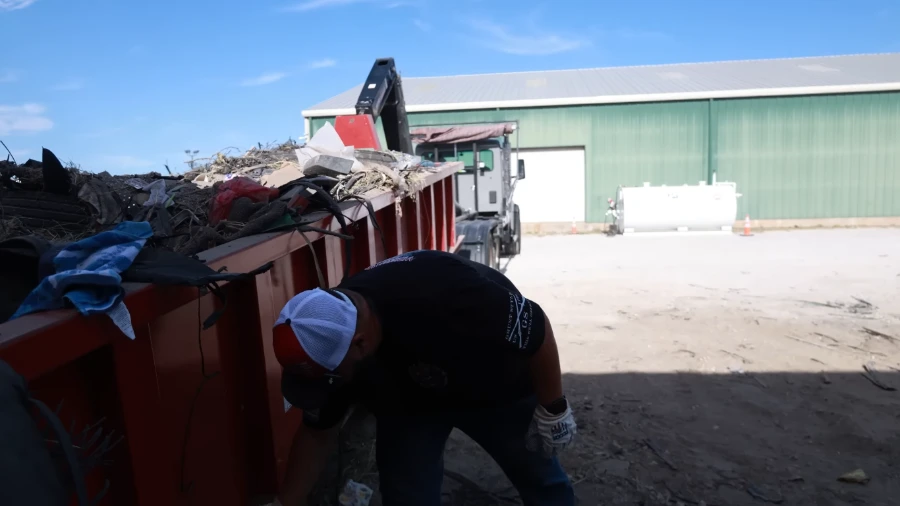 Overfilled roll-off dumpster with debris piled above the top rim